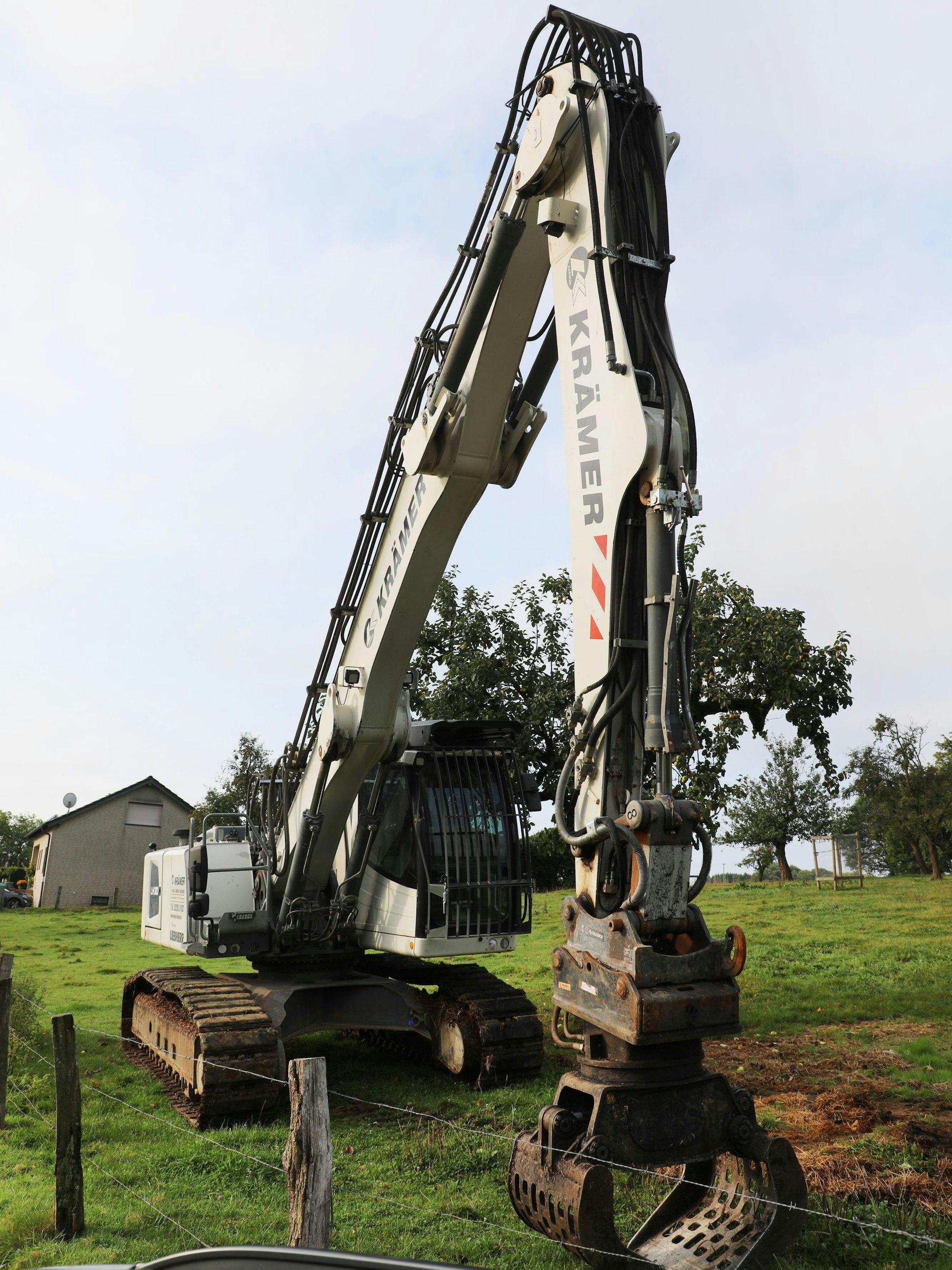 Ein großer Abrissbagger steht auf einer Wiese bei Kürten-Dürscheid.