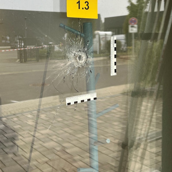 An einer Glastüre ist deutlich ein Einschussloch zu erkennen.