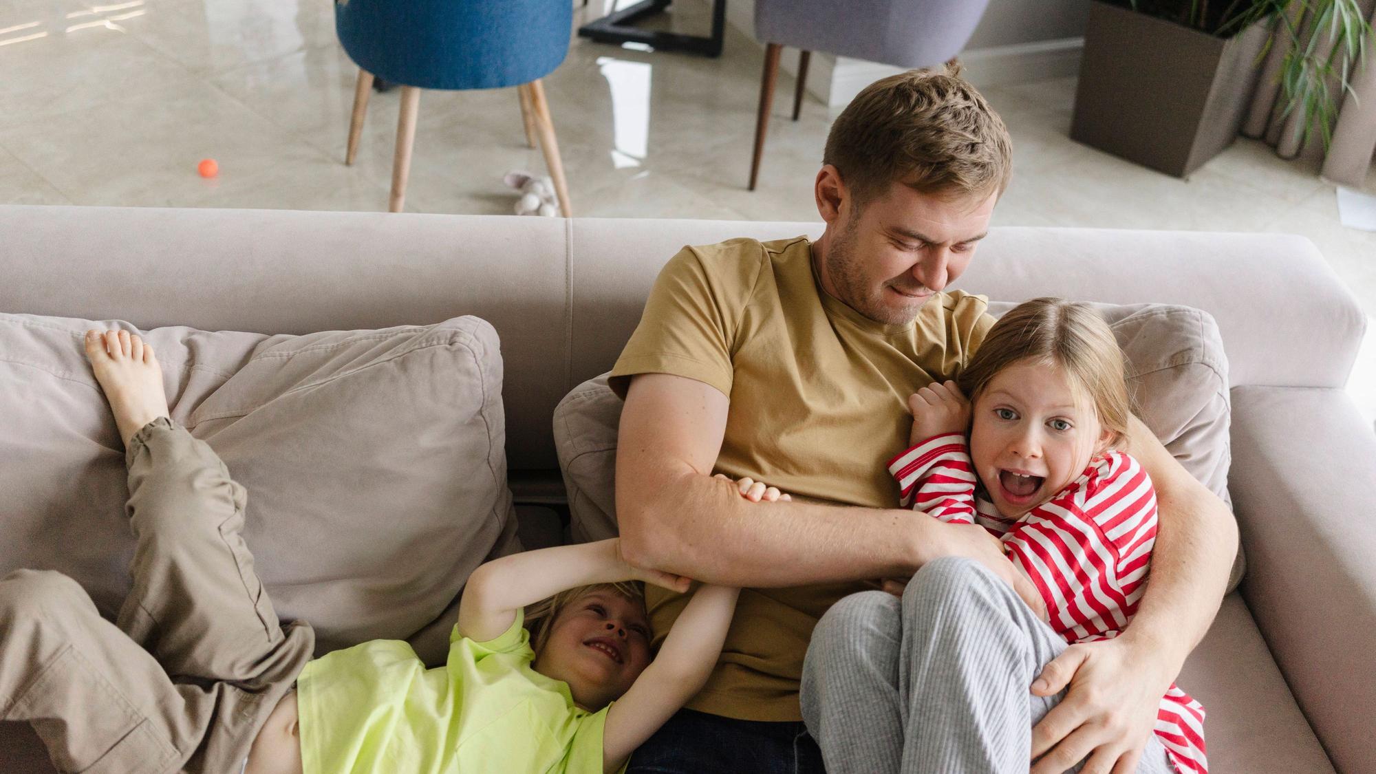 Vater spielt mit zwei Kindern auf der Couch