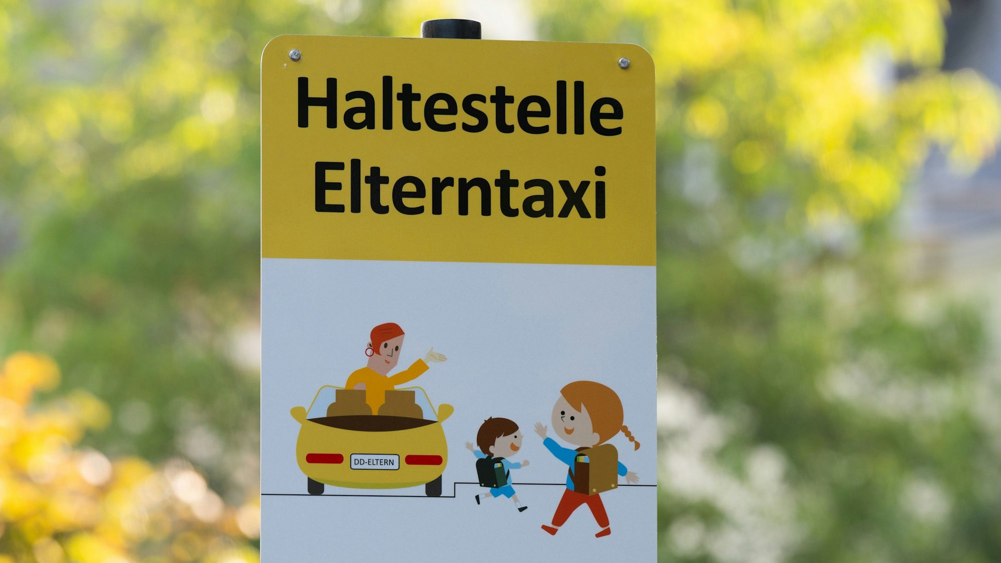 Ein Schild mit der Aufschrift „Haltestelle Elterntaxi“ steht vor einer Grundschule.
An manchen Schulen gibt es extra Haltezonen für Elterntaxis.