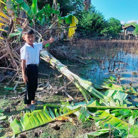 HANDOUT - 19.10.2022, Laos, Soukhoumma District: Ein neunjähriger Junge in Laos zeigt die Schäden in seinem Dorf nach einem Taifun.