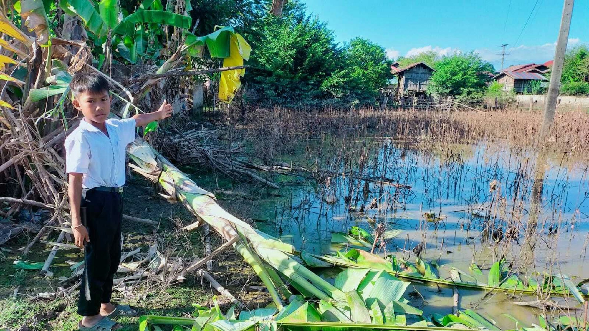 HANDOUT - 19.10.2022, Laos, Soukhoumma District: Ein neunjähriger Junge in Laos zeigt die Schäden in seinem Dorf nach einem Taifun.
