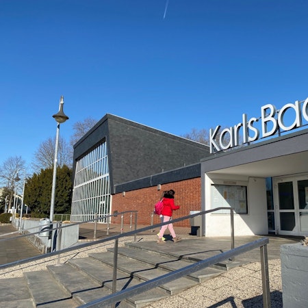 Auf dem Bild ist zu sehen, wie eine Dame die Treppen zum Karlsbad hochsteigt.