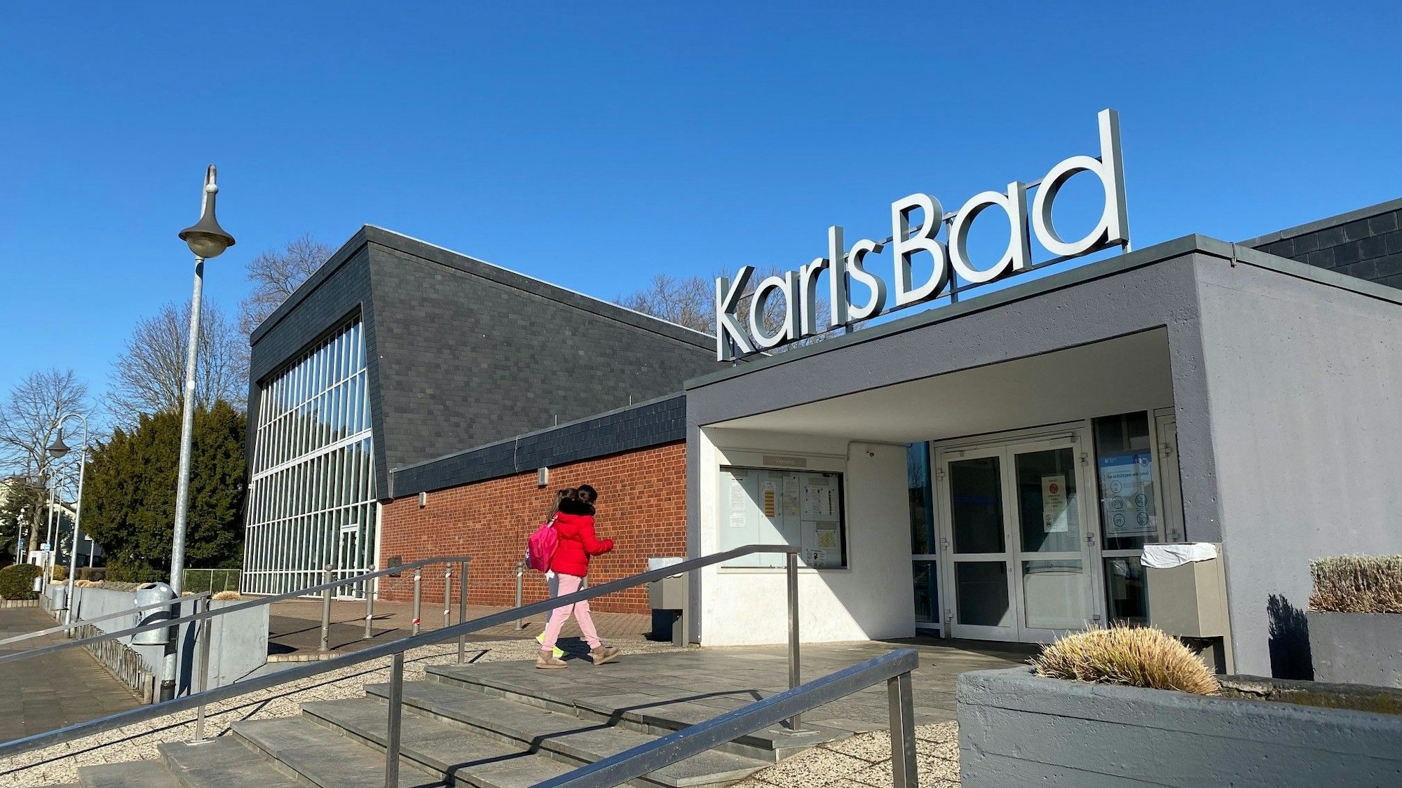 Auf dem Bild ist zu sehen, wie eine Dame die Treppen zum Karlsbad hochsteigt.