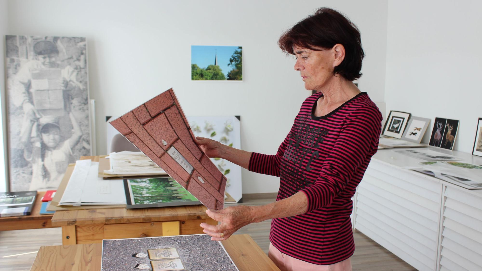 Auf dem Bild ist die Künstlerin in ihrem Atelier zu sehen. Sie betrachtet einen großen Abdruck eines ihrer Fotos.