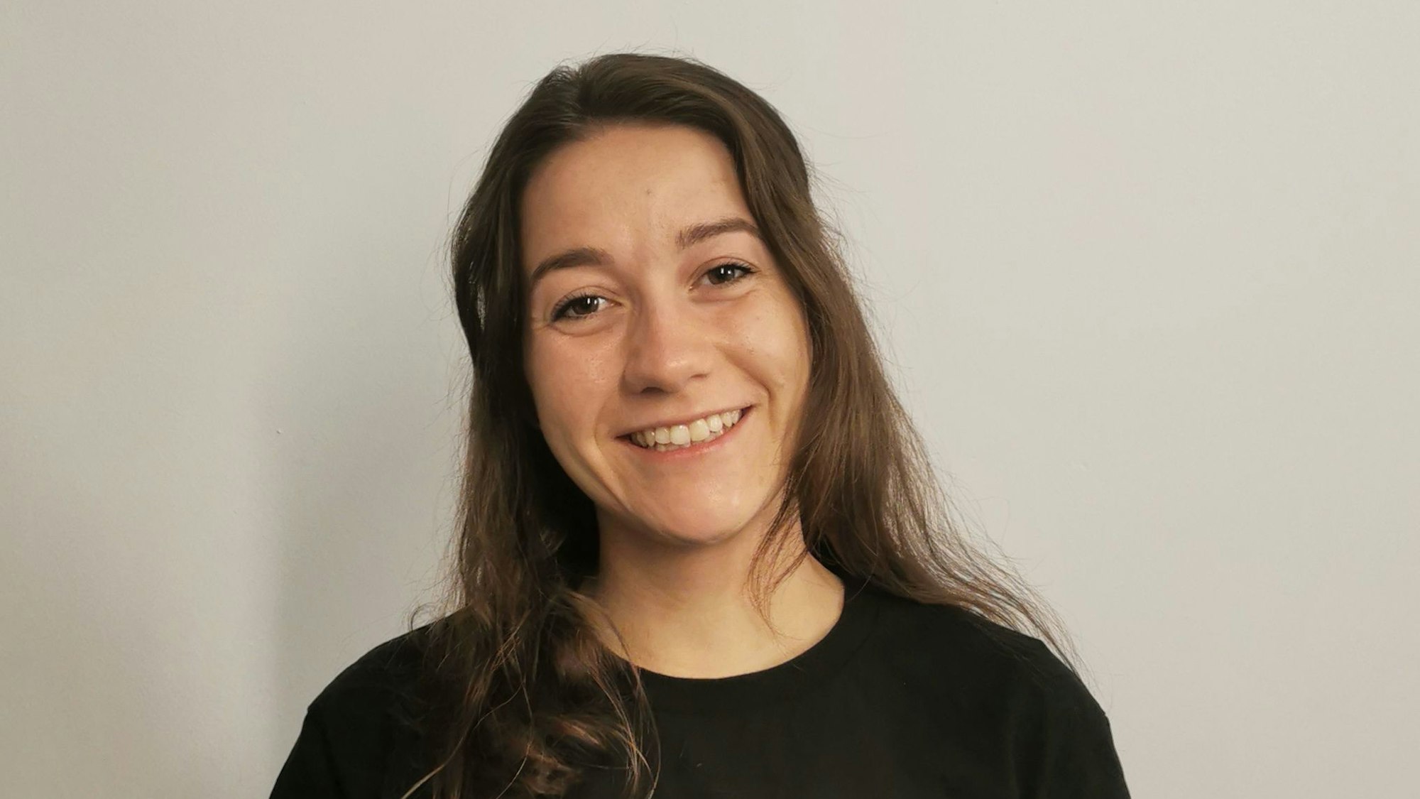 Zu sehen ist eine Frau mit dunklen langen Haaren in einem schwarzen T-Shirt.