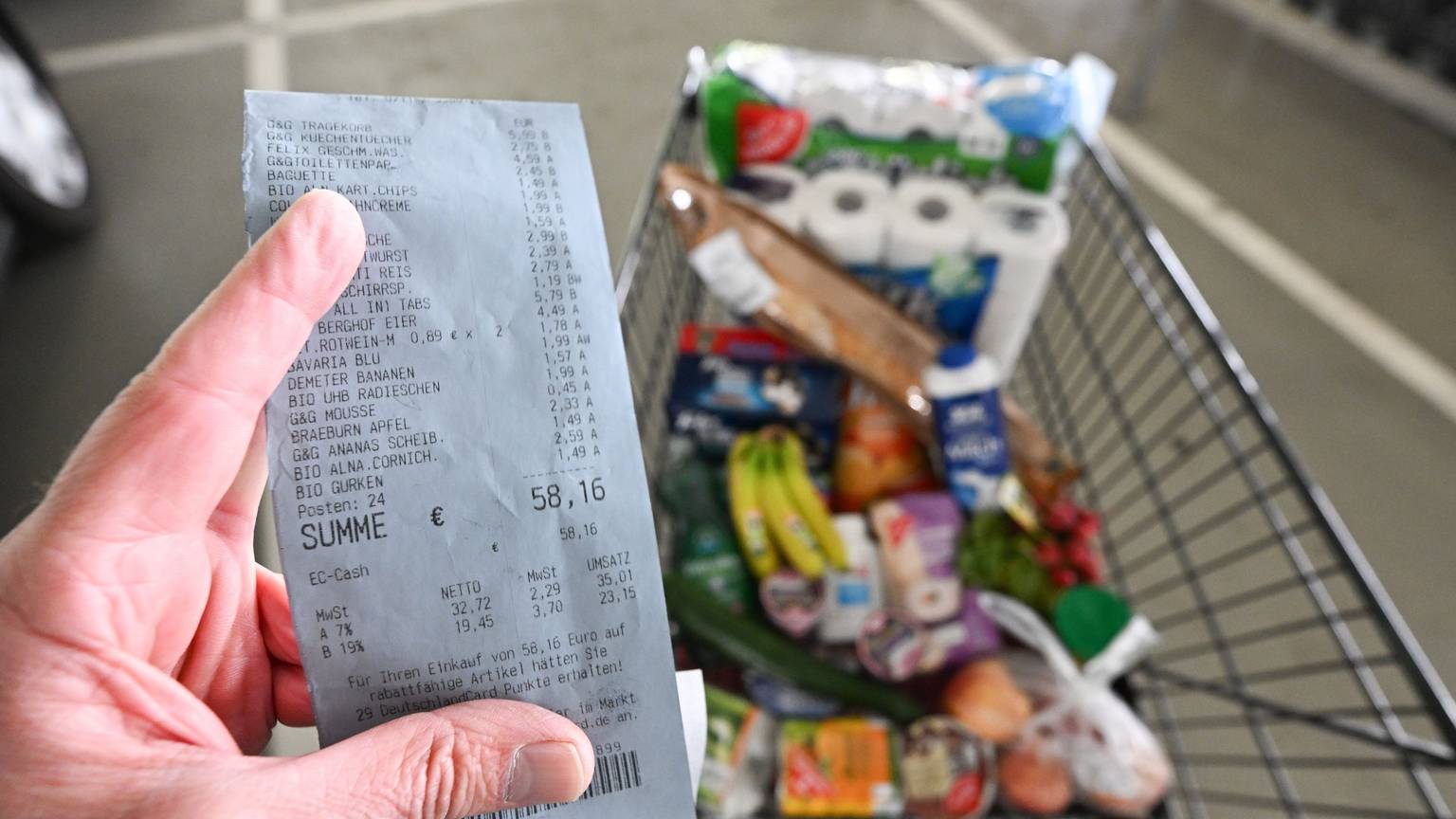 Ein Verbraucher hält nach einem Einkauf in einem Supermarkt einen Kassenzettel in der Hand.