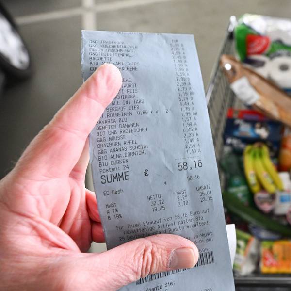 Ein Verbraucher hält nach einem Einkauf in einem Supermarkt einen Kassenzettel in der Hand.