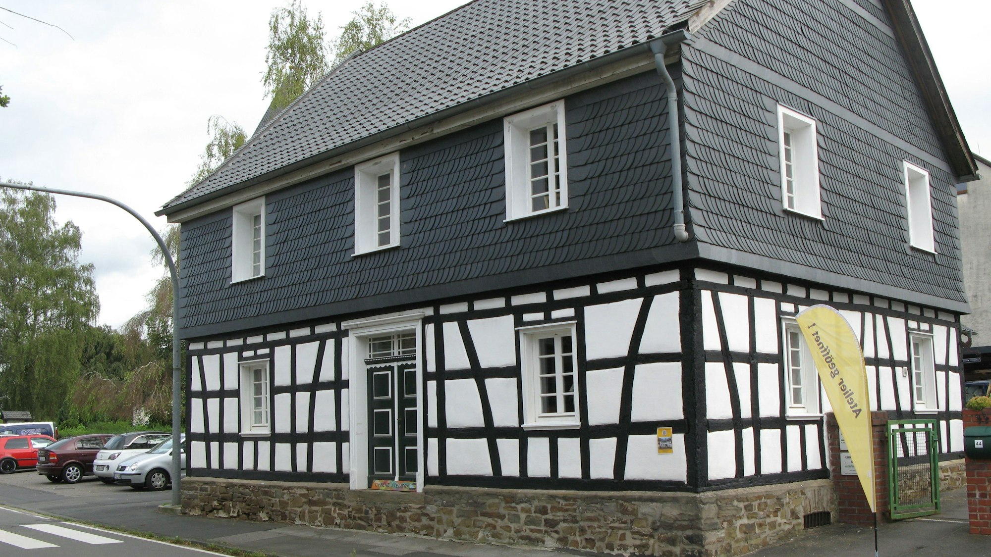 Das Bild zeigt ein saniertes Fachwerkhaus mit Schieferfassade im Obergeschoss.