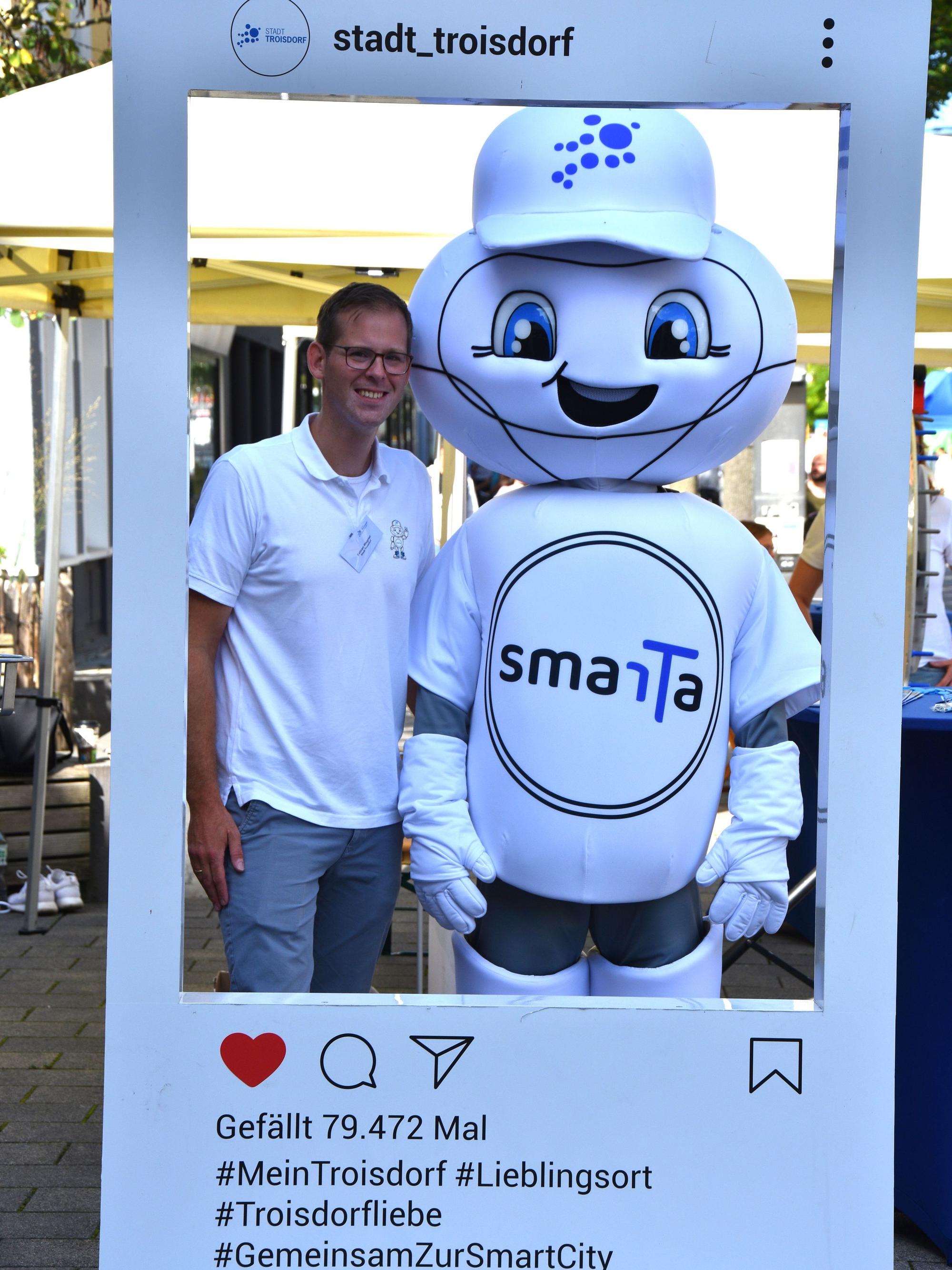 Ein Mann steht neben einem Maskottchen in einem Bilderrahmen.