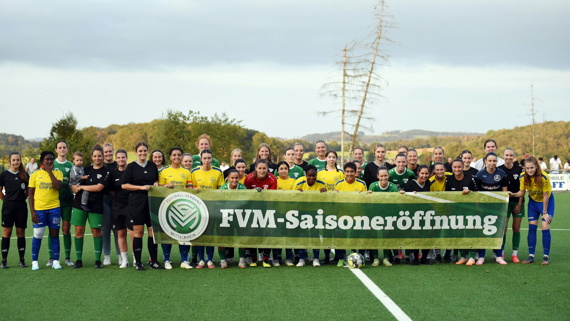 Gruppenfoto der Fußballfrauen des TuS Homburg-Bröltal und des SC West. Alle halten gemeinsam ein Banner in den Händen, auf dem steht: „FVM-Saisoneröffnung“.