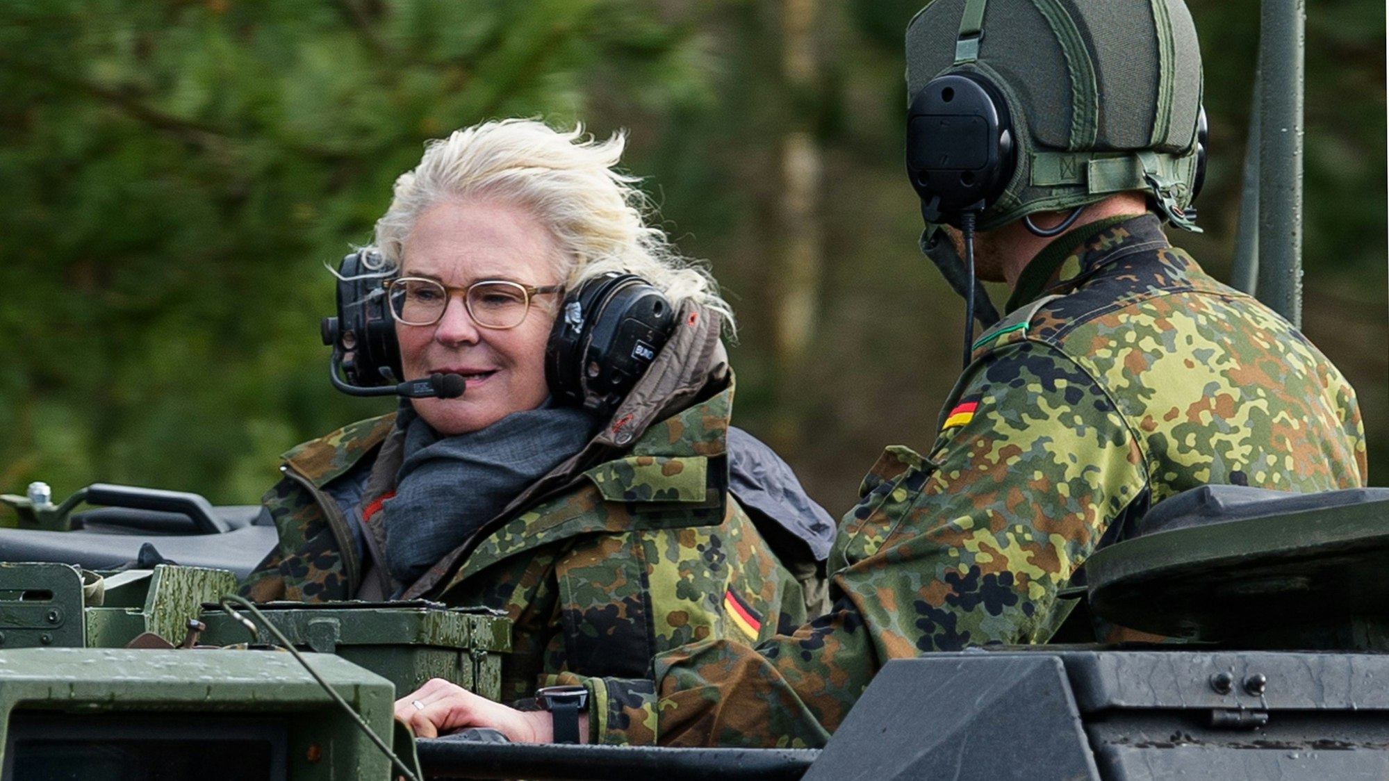 Christine Lambrecht (l, SPD), damals Verteidigungsministerin, fährt bei ihrem Besuch der Panzerlehrbrigade 9 auf einem Panzer mit. Die SPD-Politikerin will nun ein Buch schreiben. (Archivbild)