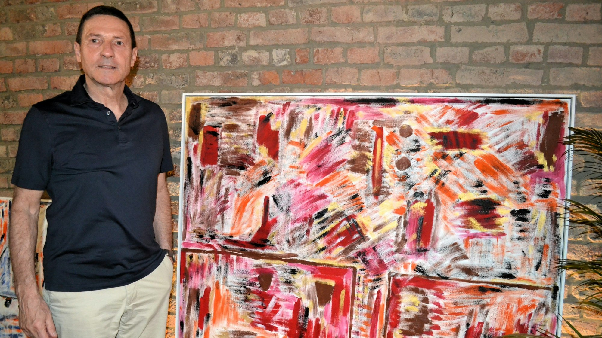 Ein Mann steht neben einem abstrakten Gemälde.
