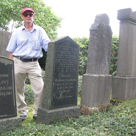 Ein Mann steht zwischen zwei Grabsteinen auf einem alten jüdischen Friedhof.