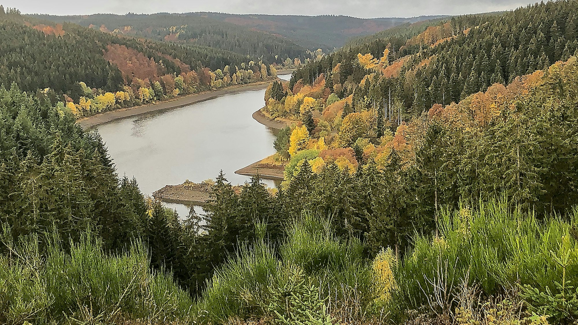 Ein großer See liegt zwischen bewaldetet Hügeln.