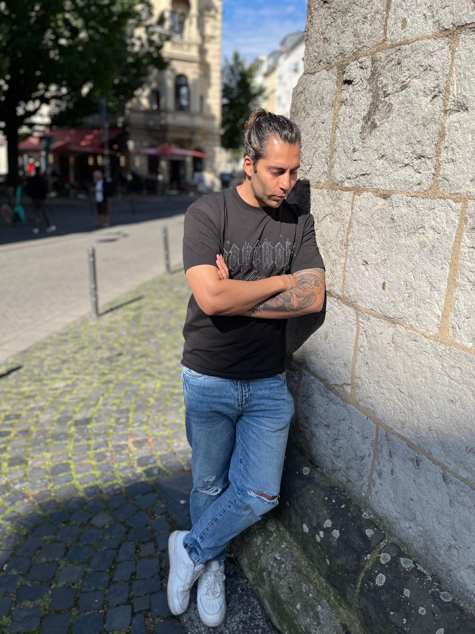 Siavash Hosseini lehnt an einer Mauer.