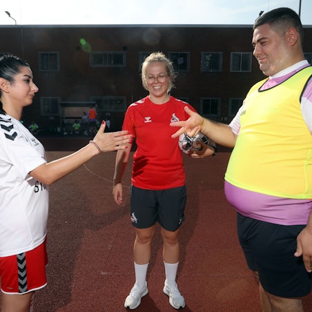 Eine Runde Schere, Stein, Papier klärt die Frage nach dem Anstoß zwischen einer Insässin der JVA (links) und einem Spieler der Inklusionsmannschaft von Germania Zündorf, Trainerin Luisa Schanze (FC-Stiftung) kontrolliert.