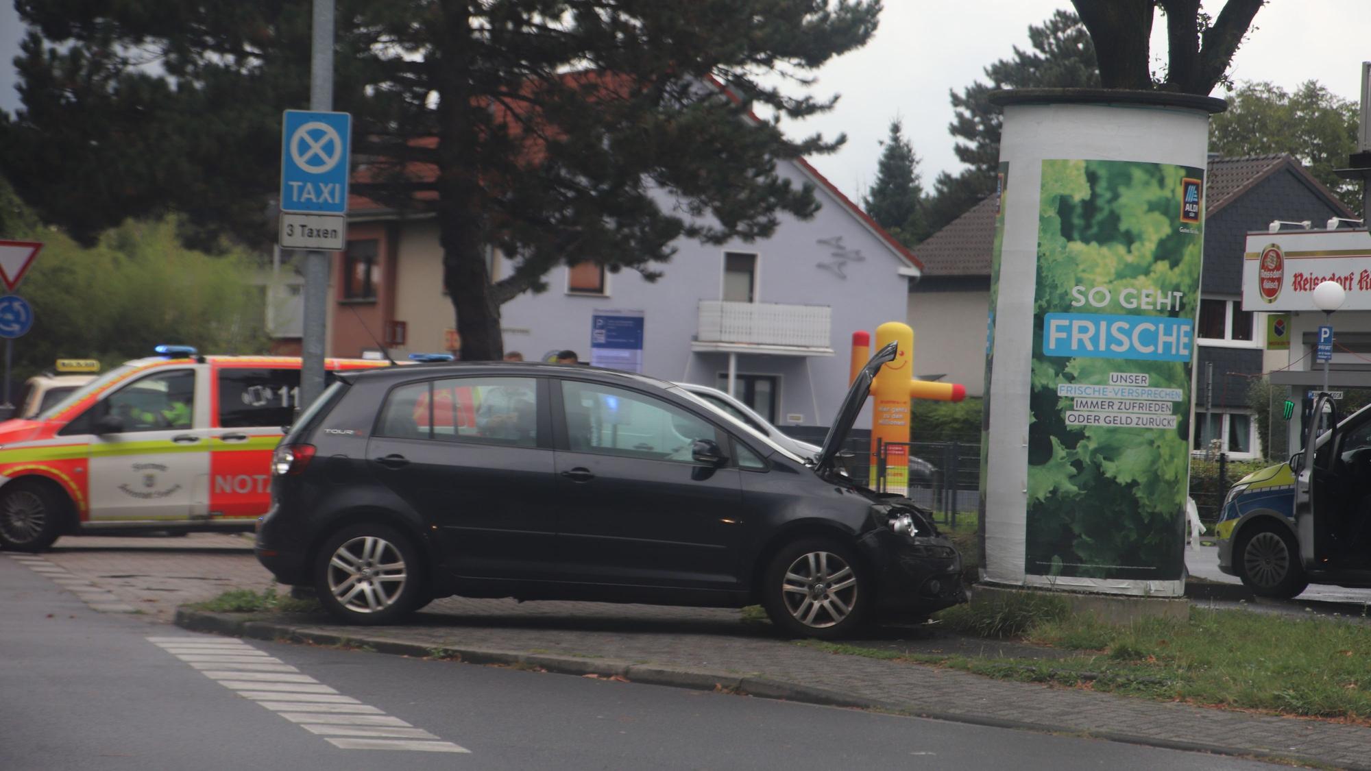 Ein Auto steht nach einem Zusammenstoß vor einer Werbesäule.