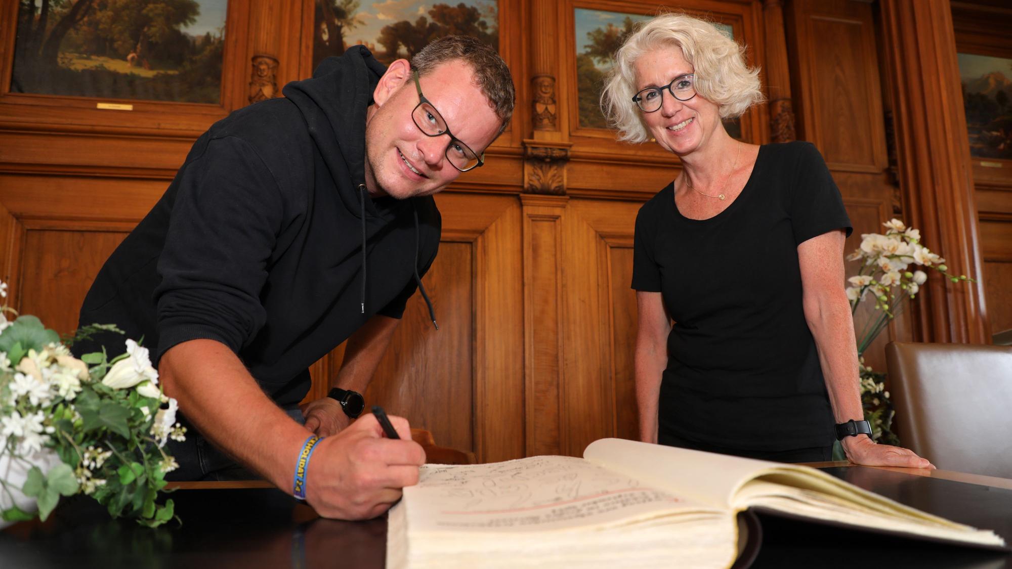 Die Lehrer Andreas Ruigk und Nicole Jakoby tragen sich ins Goldene Buch der Stadt Bergisch Gladbach ein.