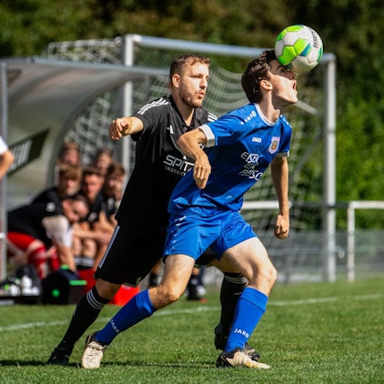 Ein Fußballer balanciert den Ball auf der Nase.