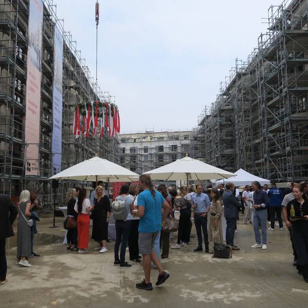 Zu sehen sind Richtfest-Besucher, die inmitten einer Wohnungsbaustelle stehen.