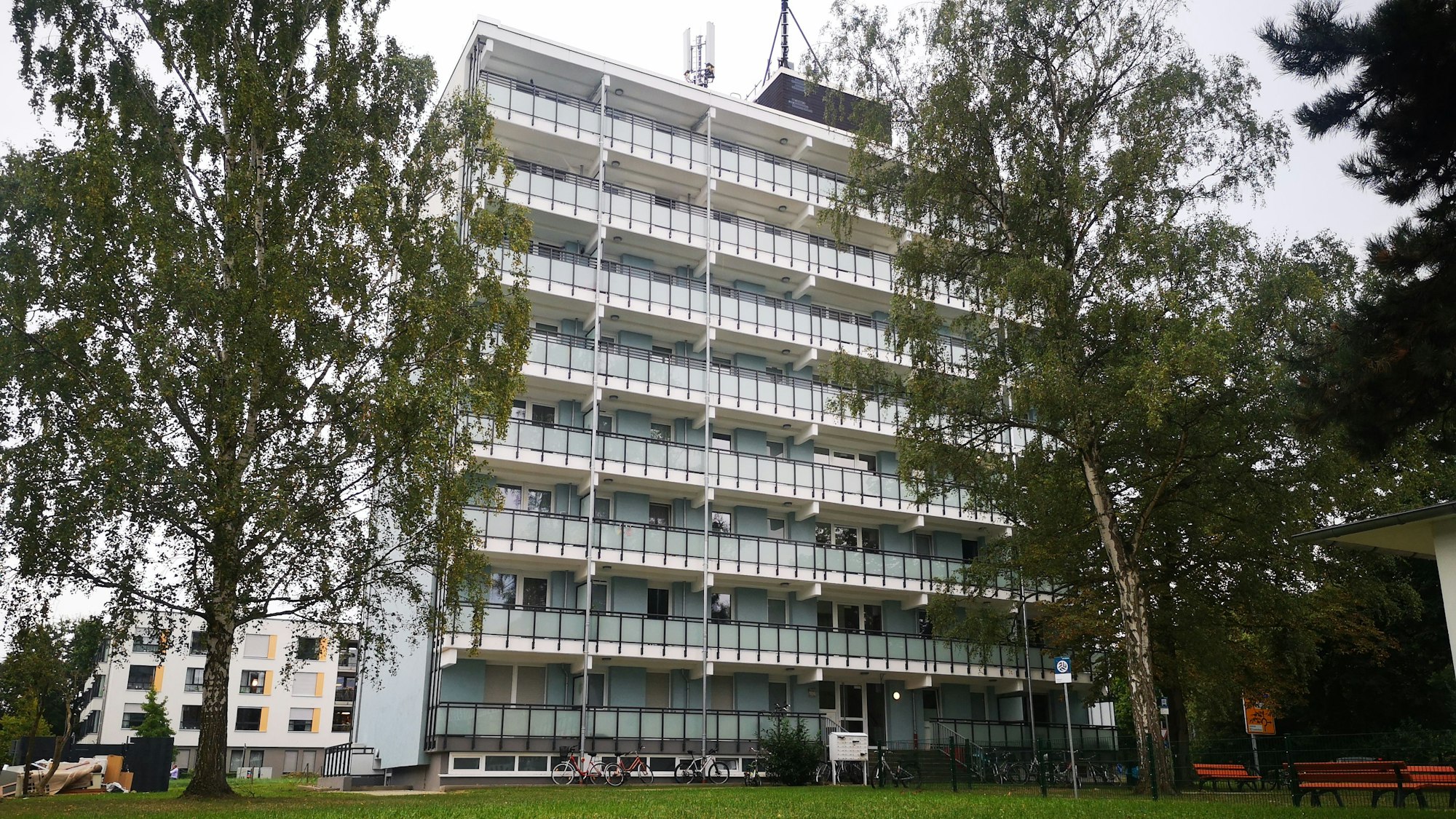 Ein Mehrfamilienhaus in Wesseling mit acht Stockwerken. Zwei Bäume rahmen das helle Gebäude links und rechts ein.