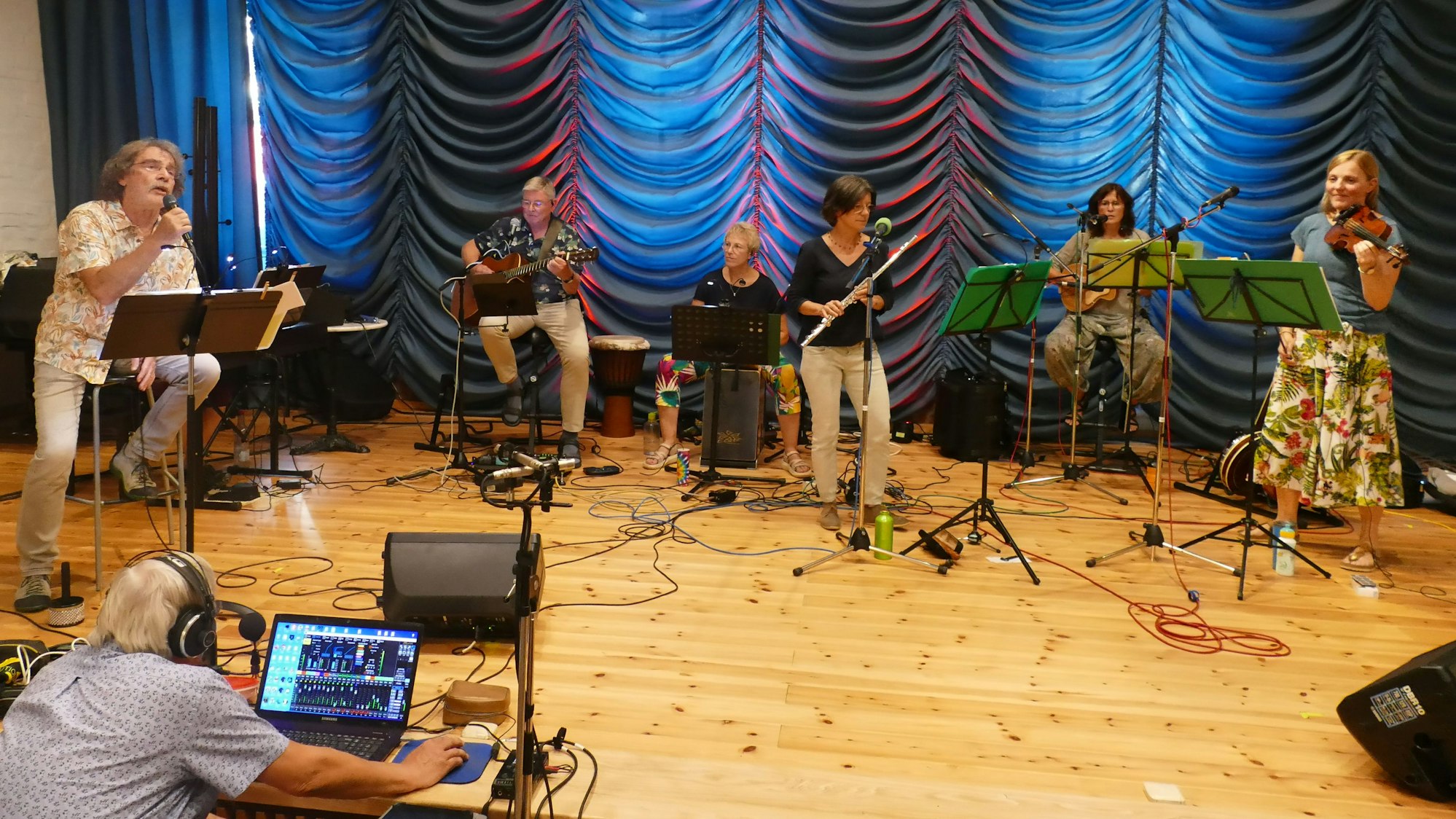 Eine Musikband mit Sänger und fünf Frauen und Männern an Instrumenten.