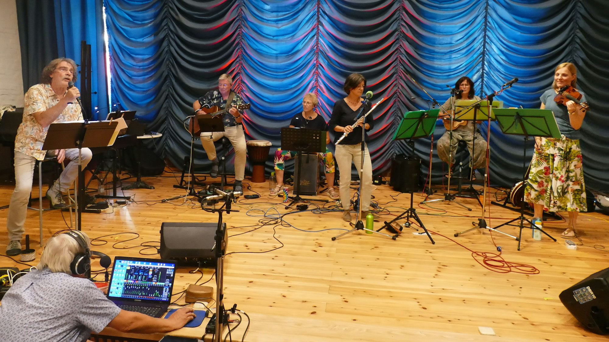 Eine Musikband mit Sänger und fünf Frauen und Männern an Instrumenten.