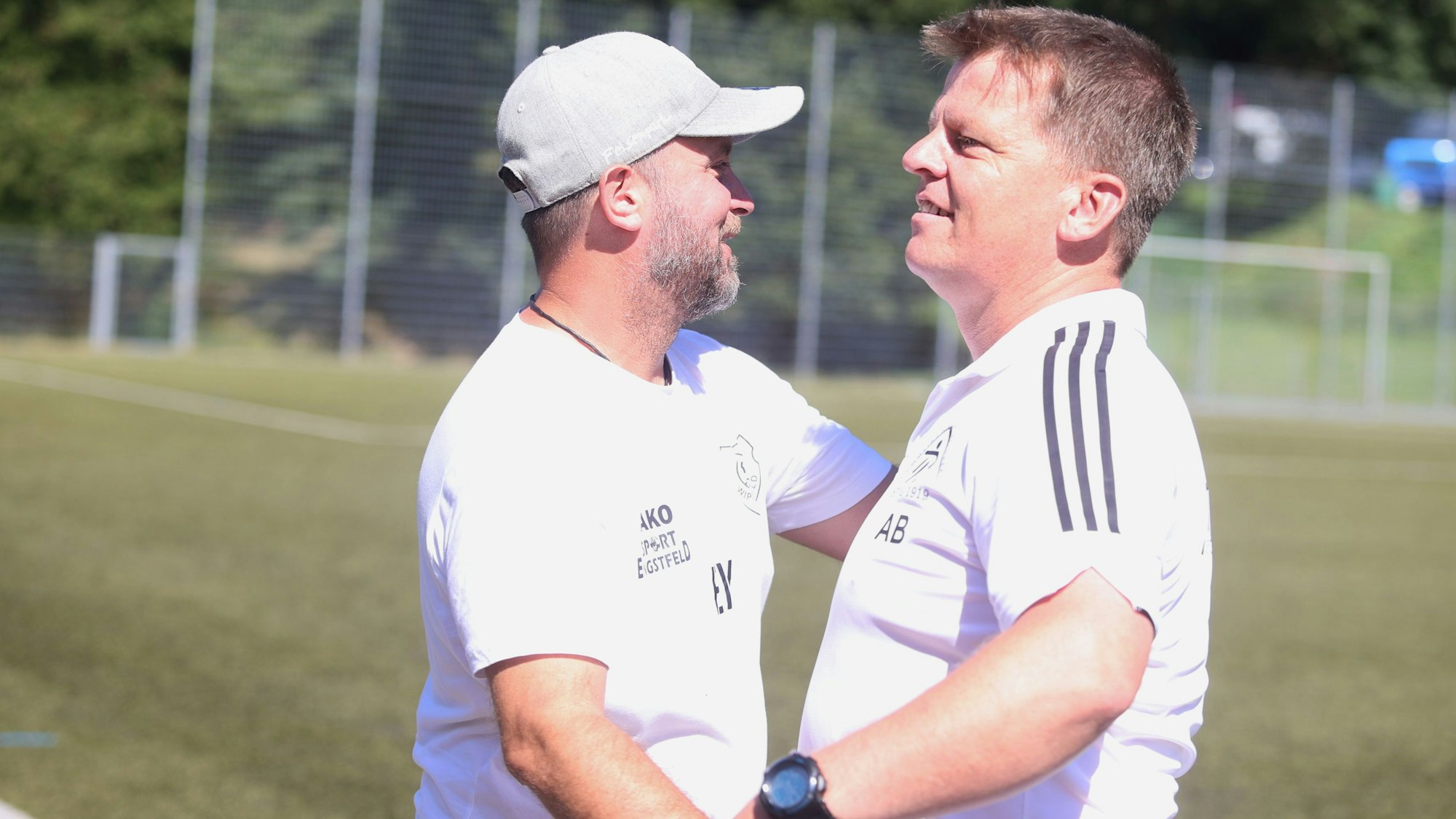 Zu sehen sind zwei Fußballtrainer, die einander die Hände geben.