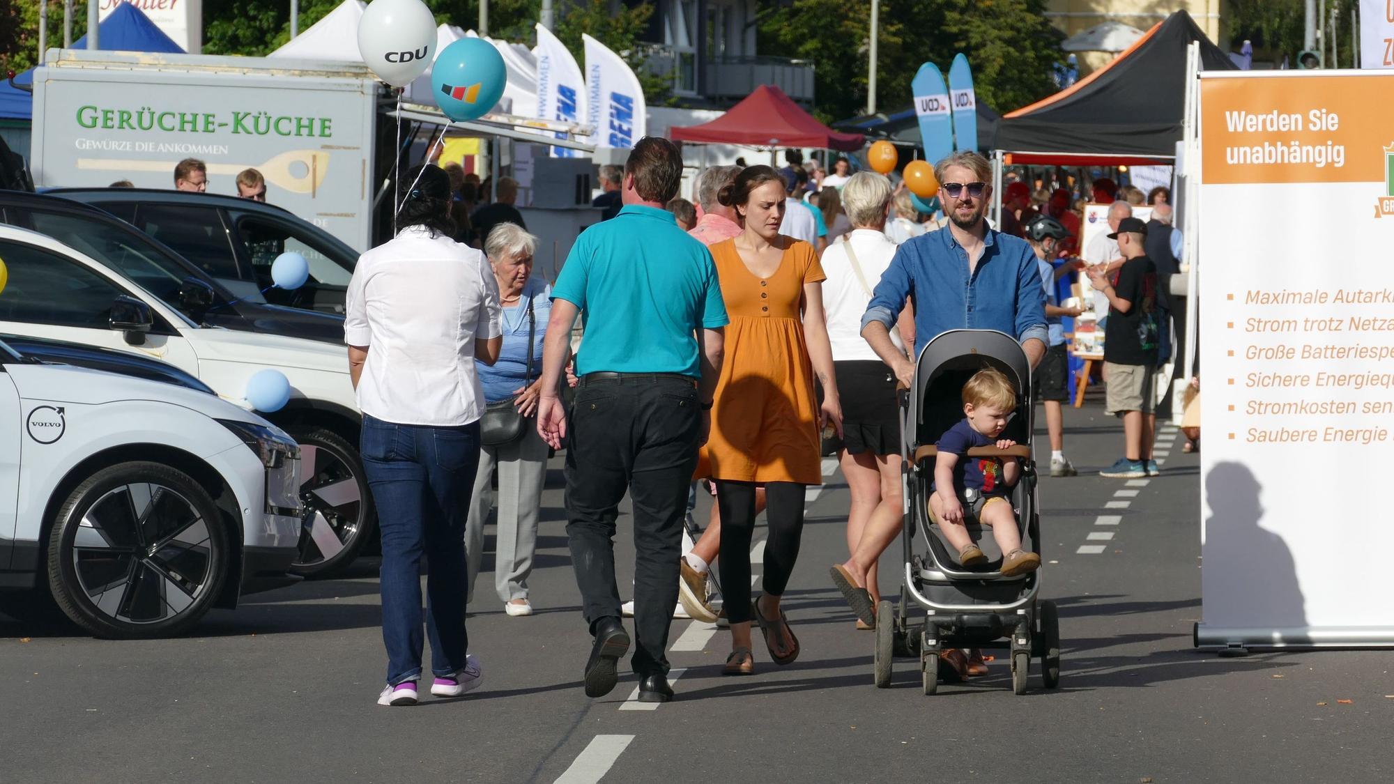 Passanten bei einem Straßenfest mit Werbeausstellung.