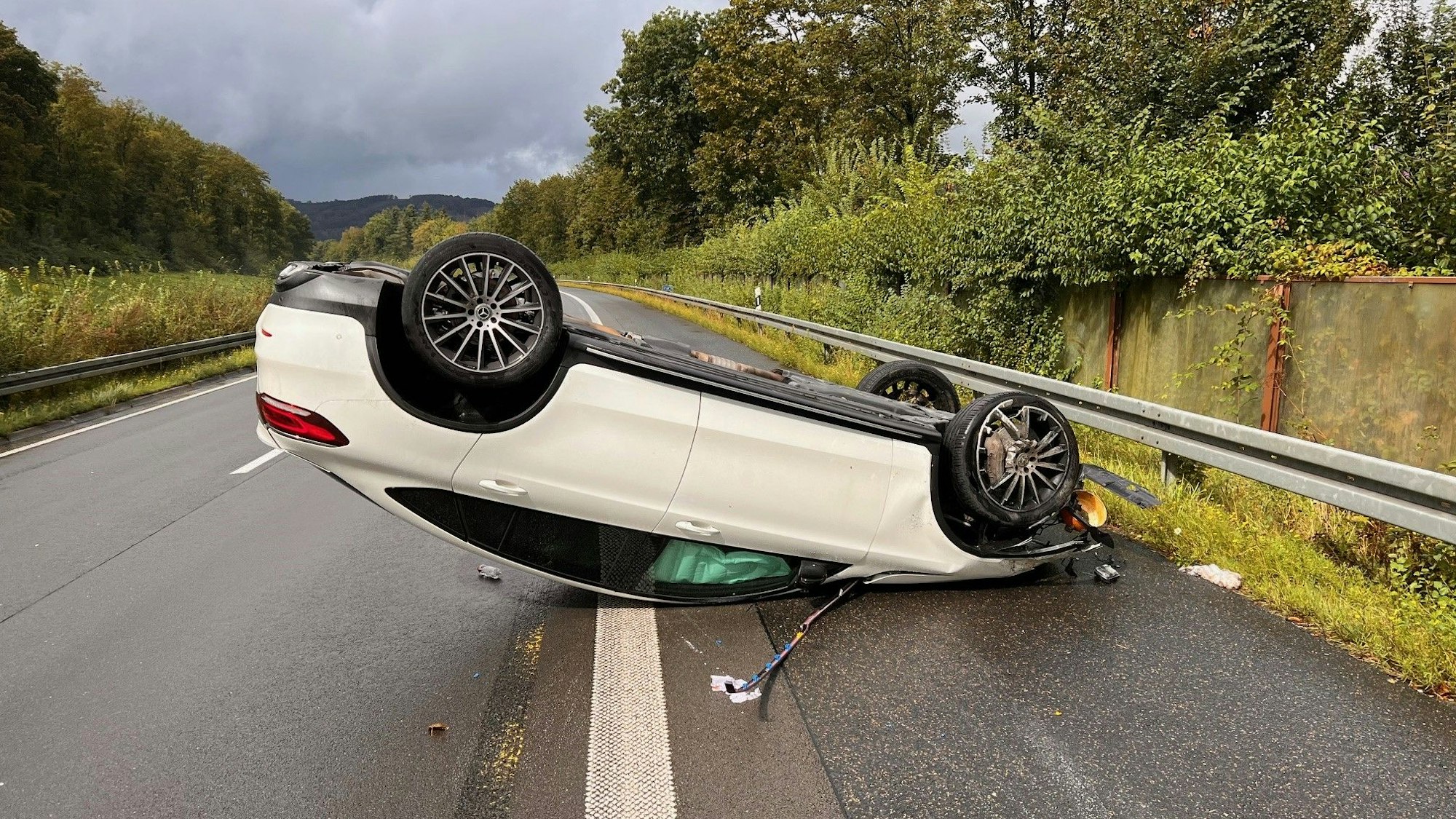 Ein weißes Fahrzeug liegt auf dem Standstreifen der Autobahn auf dem Dach.