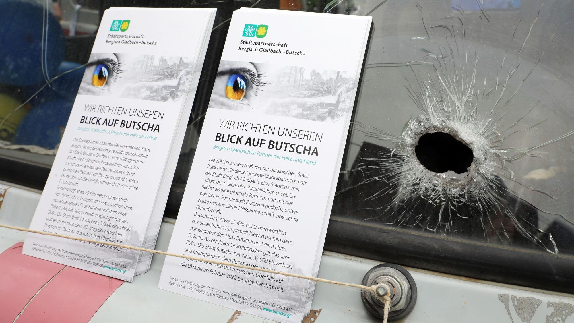 Faltblätter des Vereins zur Förderung der Städtepartnerschaft Bergisch Gladbach – Butscha stehen neben einem Loch in einer Windschutzscheibe eines ukrainischen Krankenwagens.