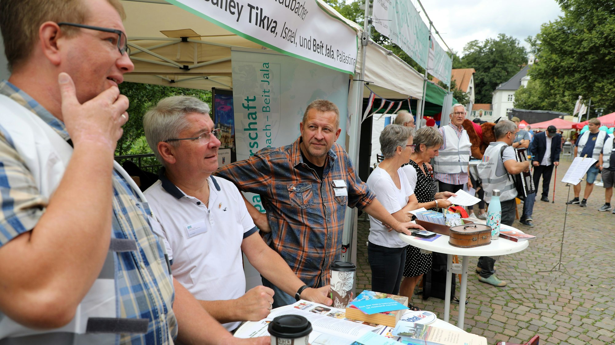 Lutz Urbach und Stephan Dekker stehen am gemeinsamen Stand der Städtepartnerschaftsvereine mit Ganey Tikva (Israel) und Beit Jala (Palästina) auf dem Stadtfest in Bergisch Gladbach.