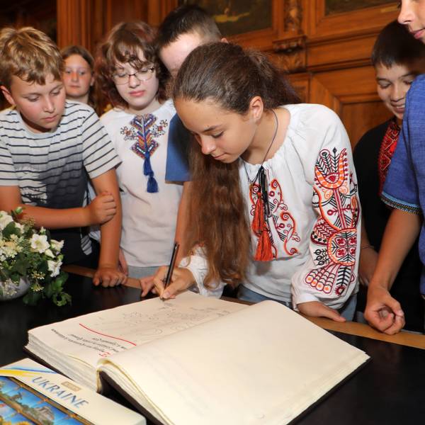 Eine ukrainische Schülerin trägt sich bei Bergisch Gladbachs Bürgermeister Frank Stein im Rathaus Stadtmitte ins Goldene Buch der Stadt ein.