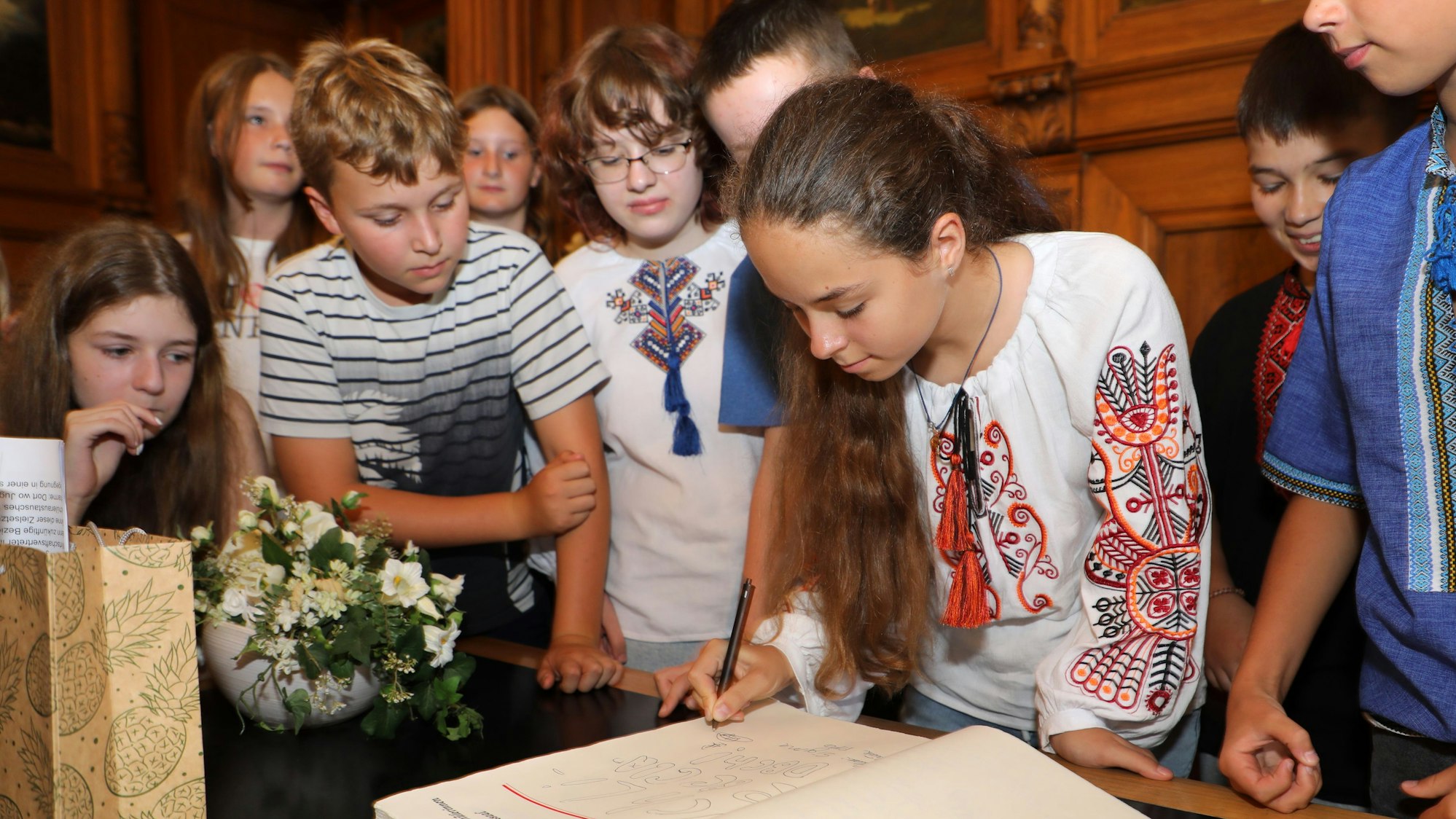 Eine ukrainische Schülerin trägt sich bei Bergisch Gladbachs Bürgermeister Frank Stein im Rathaus Stadtmitte ins Goldene Buch der Stadt ein.