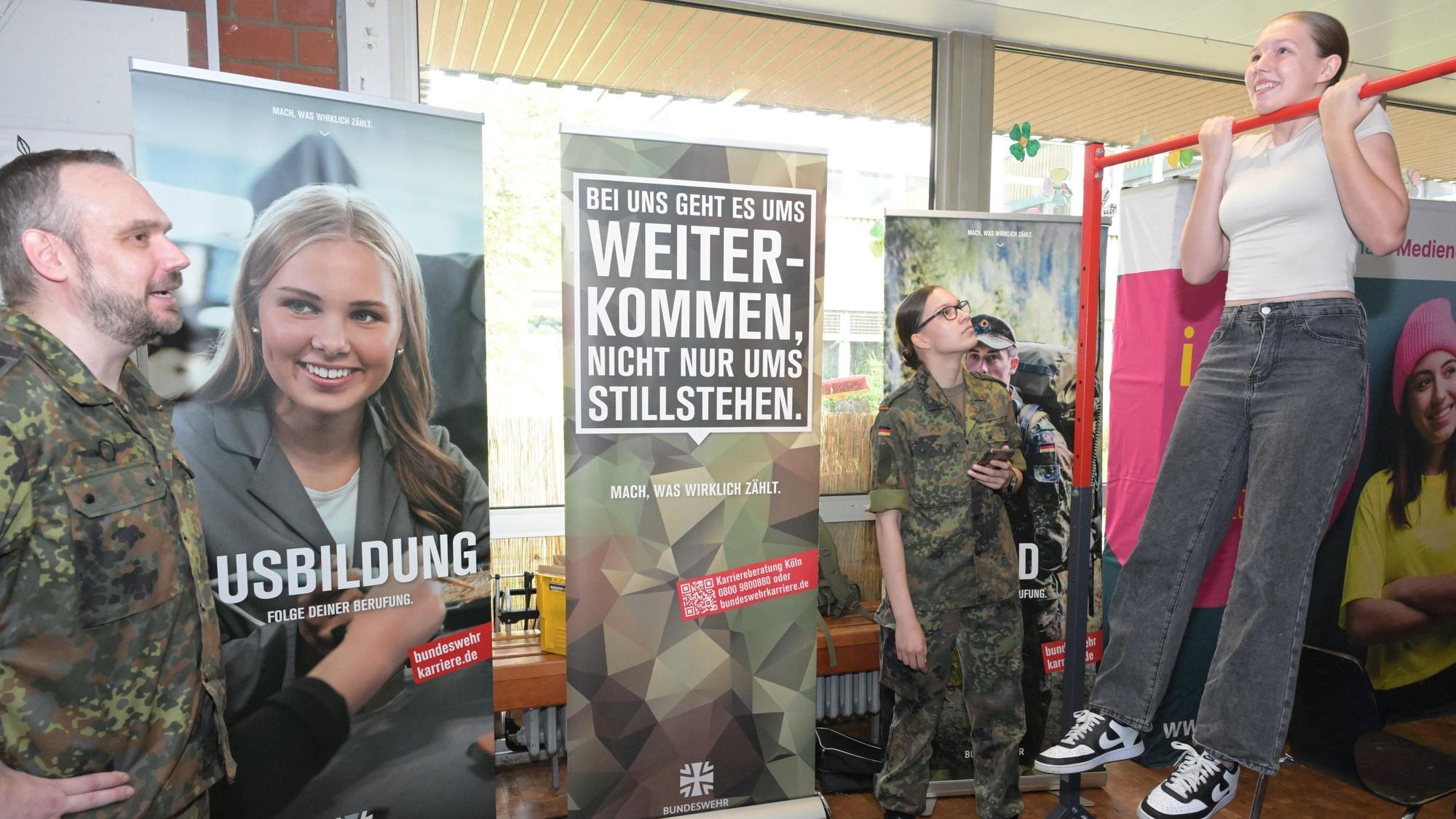 Ein junges Mädchen turnt am Reck am Stand der Bundeswehr, die ihre Ausbildungsberufe präsentiert.