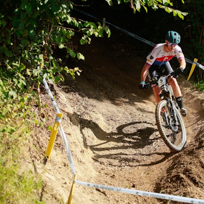 Ein E-Mountainbiker fährt bei einem Rennen über einen Waldkurs.