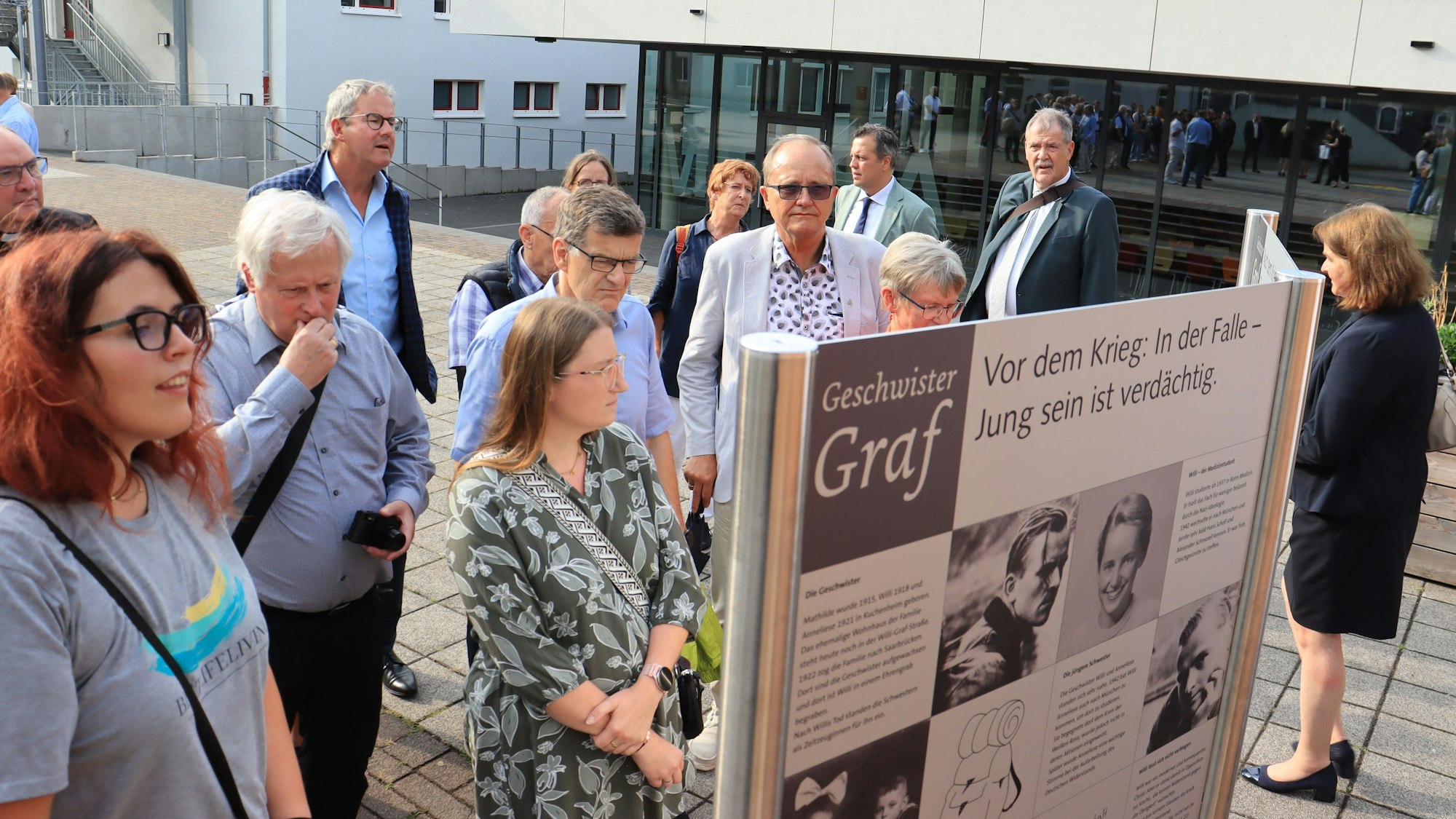 Männer und Frauen stehen vor einer Infotafel in Euskirchen, die auf die Geschwister Graf hinweist.
