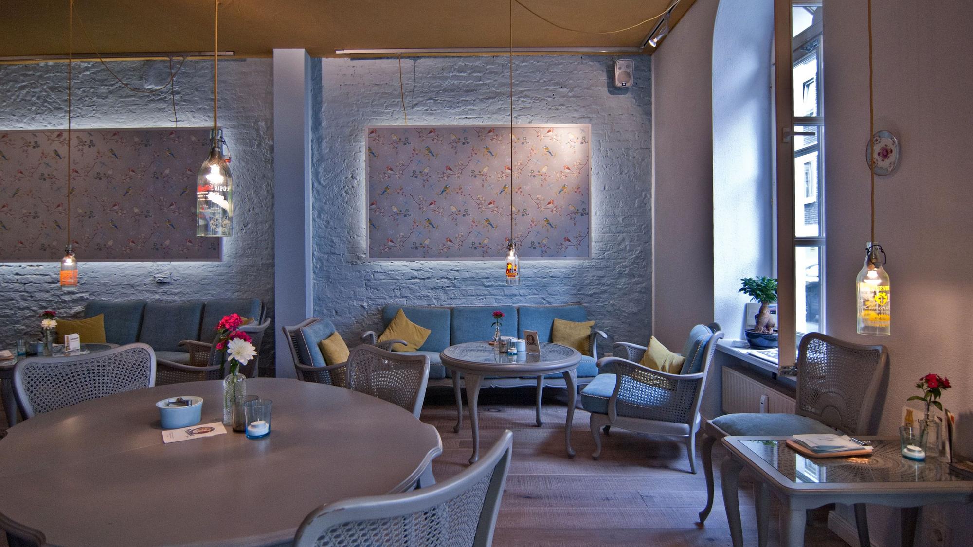 Innenraum eines Cafés mit blauen Sesseln, Sofas und Stühlen.
