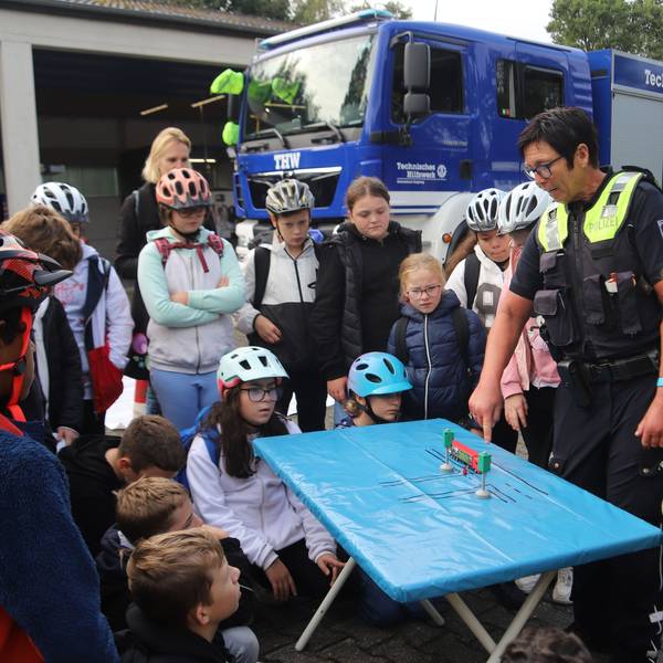 Eine Polizistin erklärt Kindern an einem Tisch eine Verkehrssituation.