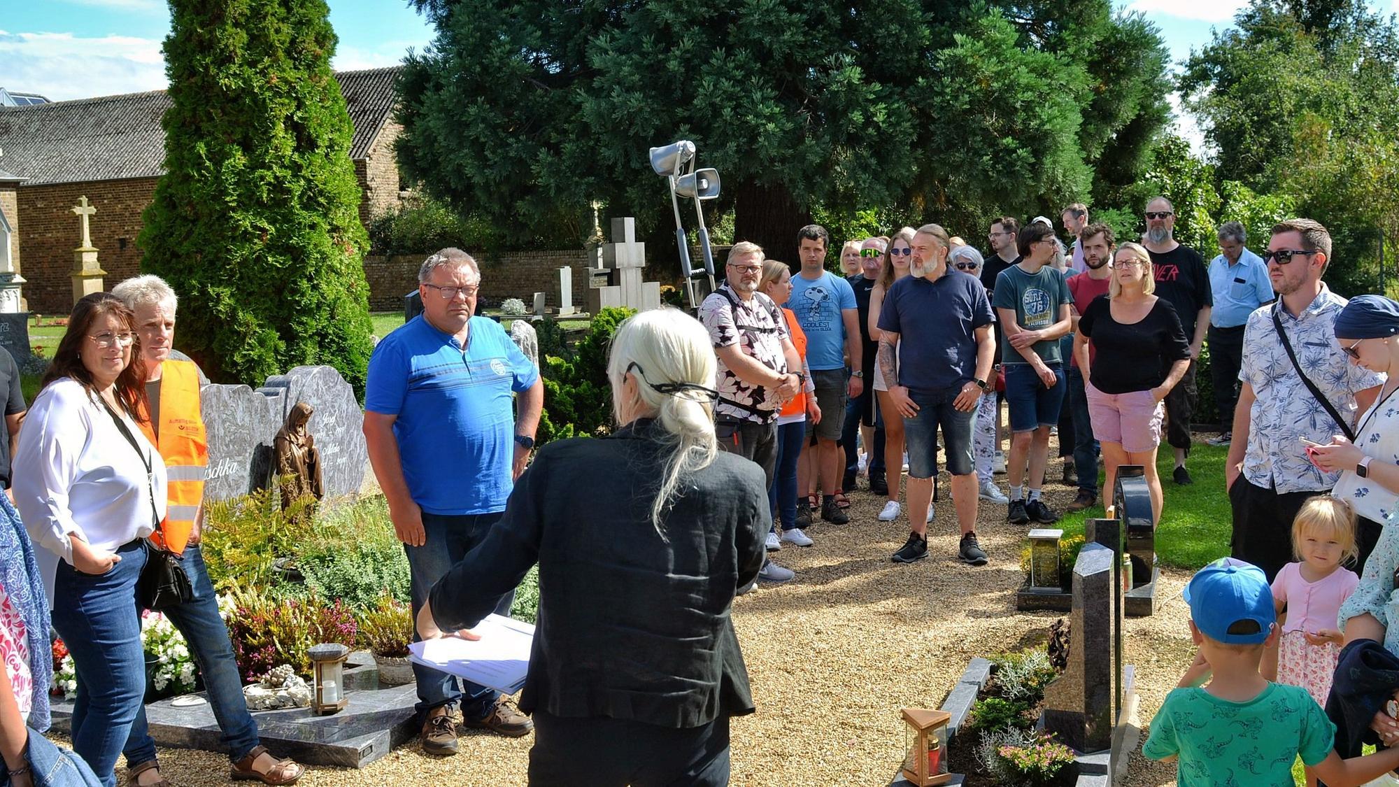 Eine Gruppe von Menschen steht auf dem Friedhof.