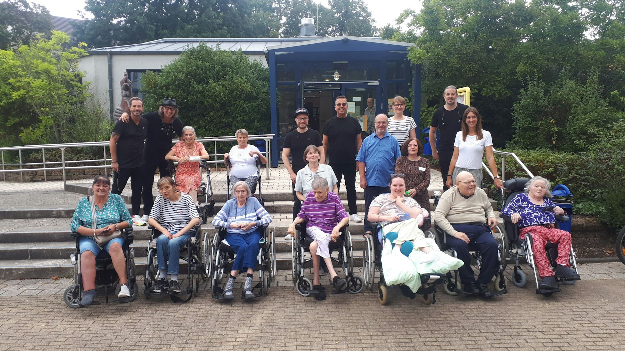 Vorfreude auf den Auftritt: Die zehn Seniorinnen und Senioren, die sich das Konzert gewünscht hatten, mit den fünf Bandmitgliedern (in Schwarz), dem Cura-Colonia-Vorsitzenden Walter Schulz (Mitte, in Blau) sowie SBK-Seniorenzentrums-Leiterin Susanne Bokelmann (rechts darüber) und dem Team der Sozialen Betreuung.