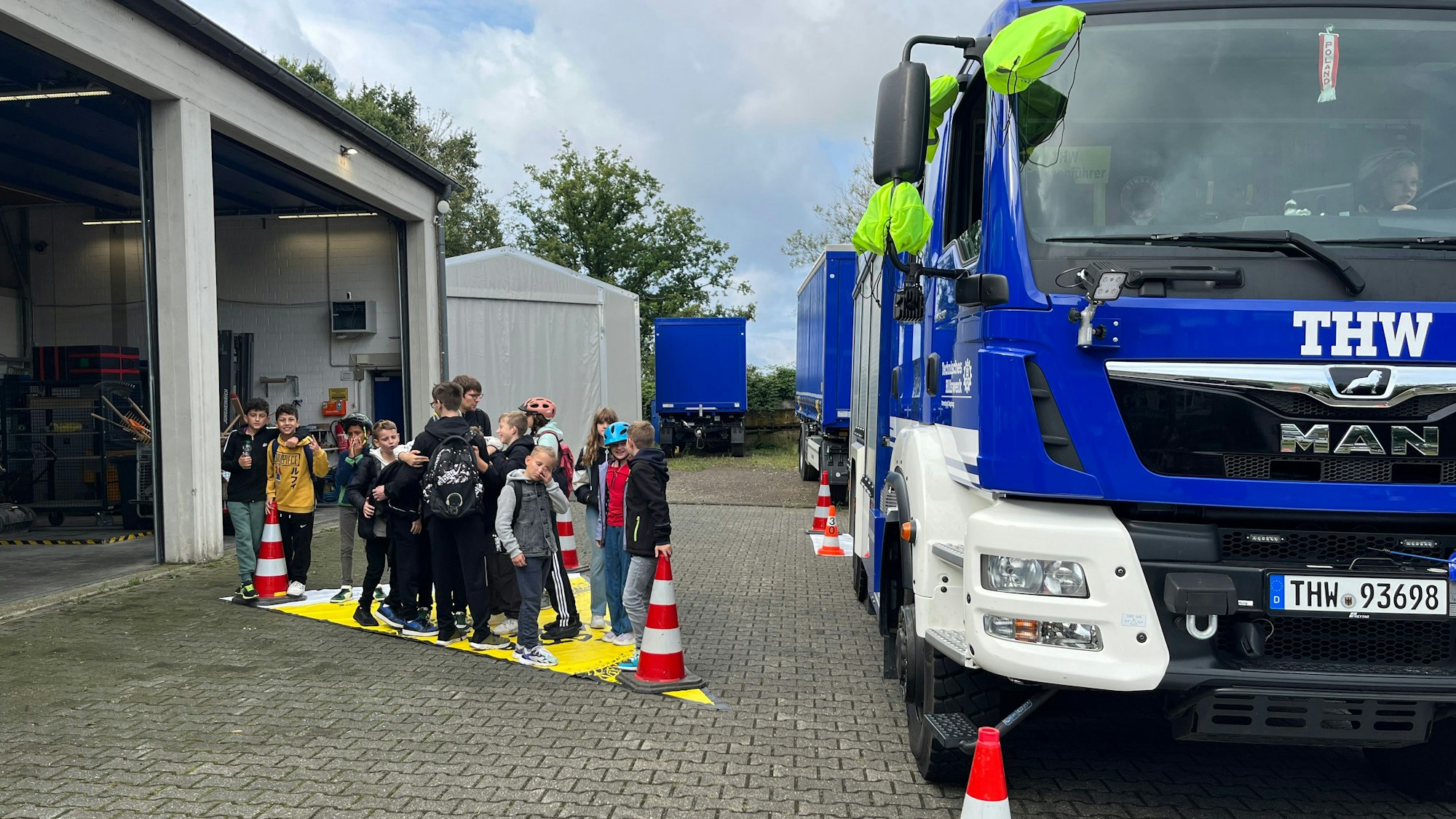 Kinder stellen sich auf einer Plane neben einem Lastwagen auf.