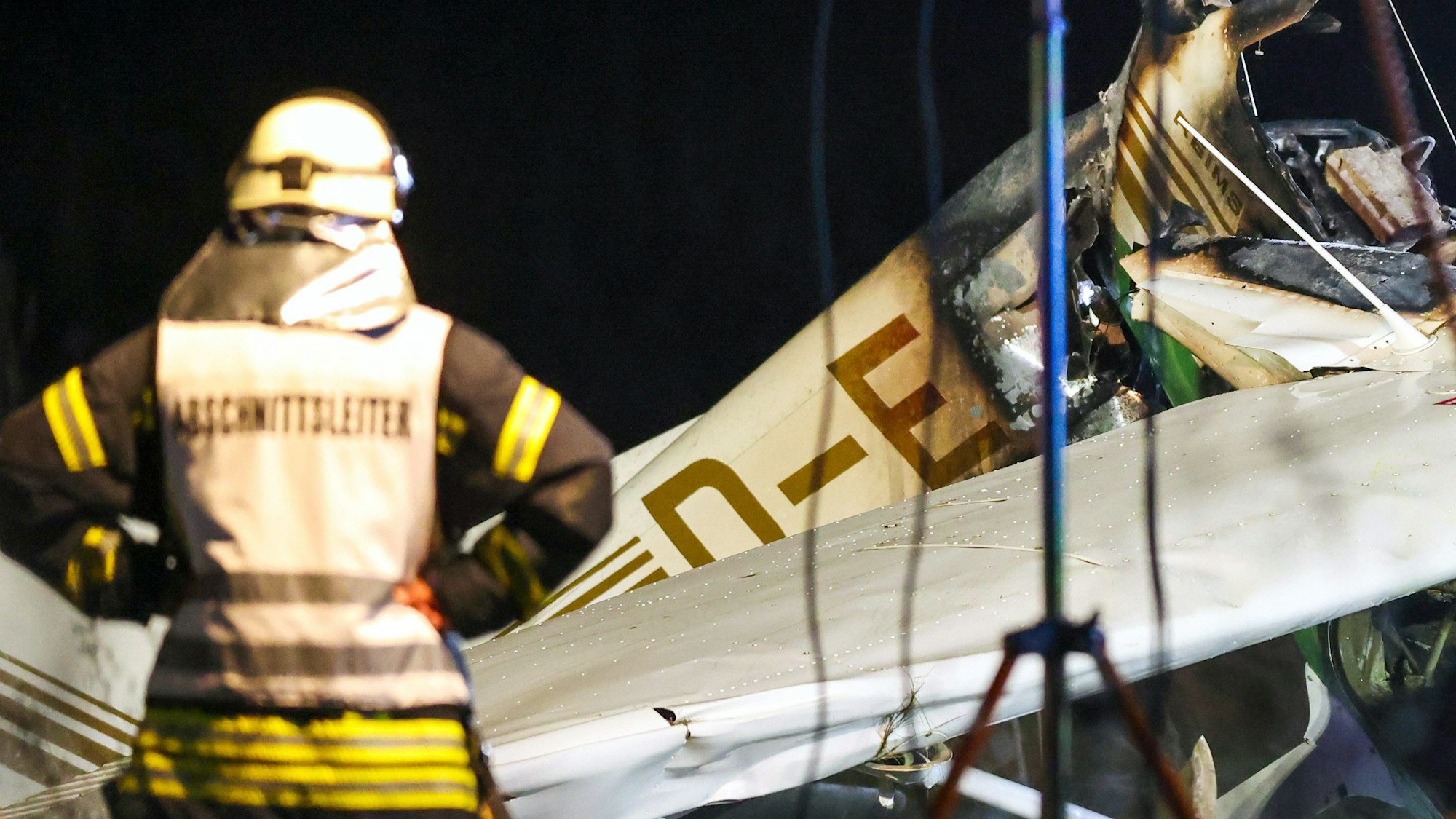 Ein Feuerwehrmann steht vor dem Wrack eines Kleinflugzeuges nach dem Absturz auf dem Gelände nahe des Flugplatzes in Bad Sassendorf.