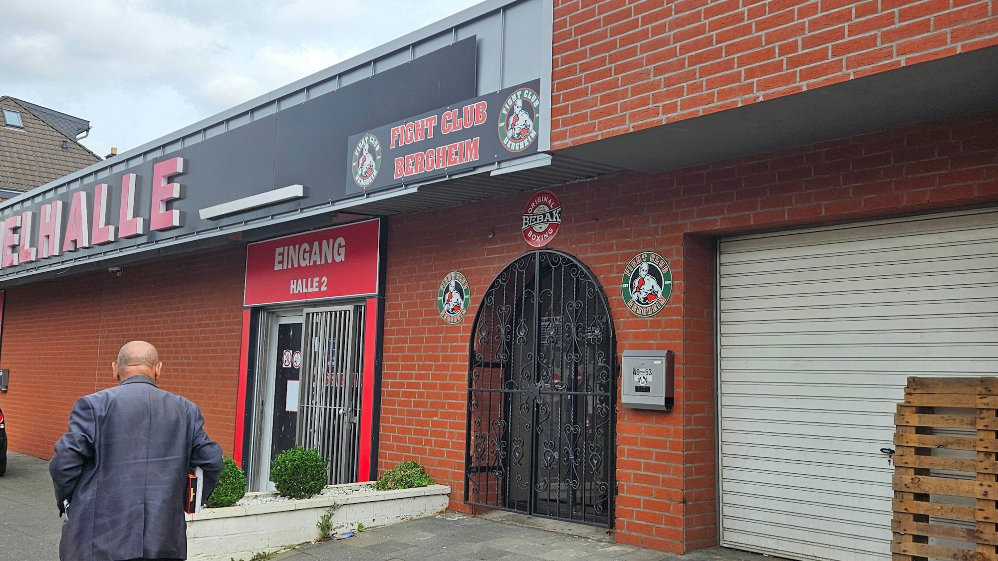 Der Eingang zum Kampfsportverein „Fight Club Bergheim“. Neben einer Gittertür hängen Logos des Vereins.