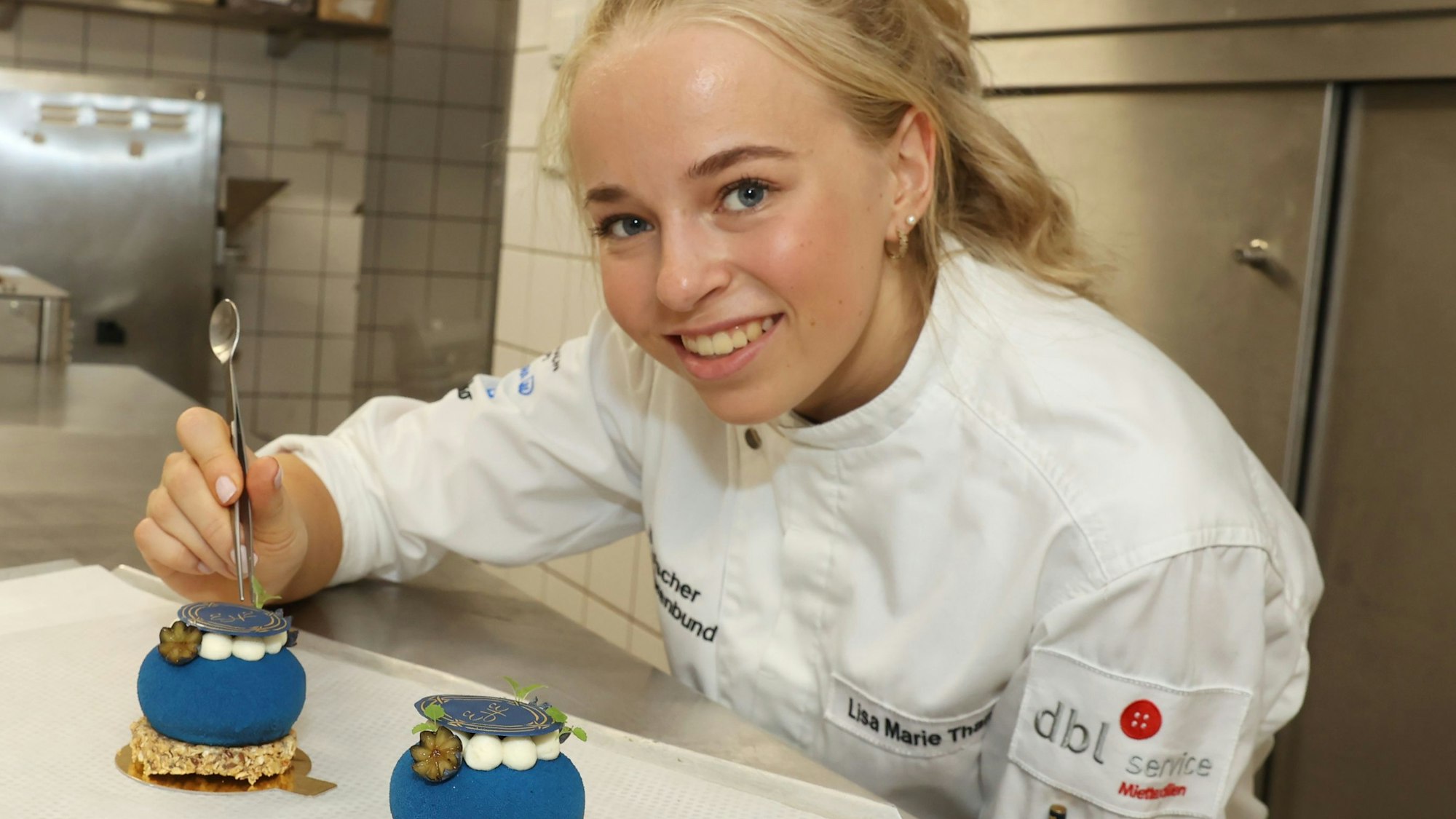 Die 22-jährige Lisa Marie Than in der Küche des Excelsior Hotels mit zwei blauen Törtchen.