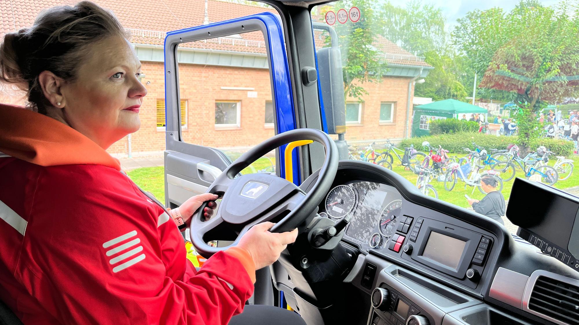 Eine Frau sitzt am Lenker eines Lastwagens.