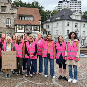 15 Teilnehmende stehen vor dem Rathaus und tragen pinke Westen.