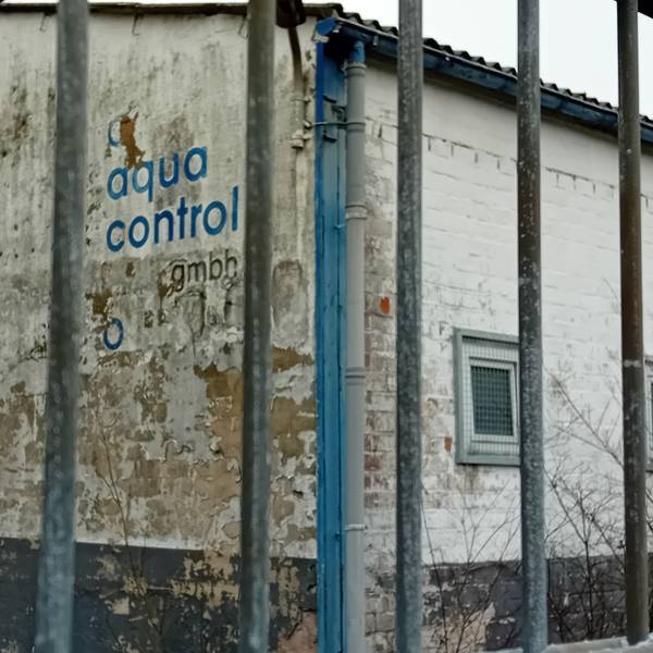 Der Schriftzug der Firma Aqua Control hinter einem Absperrgitter.