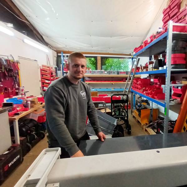 Ein Mann steht in einer Werkstatt an einer Schneidemaschine